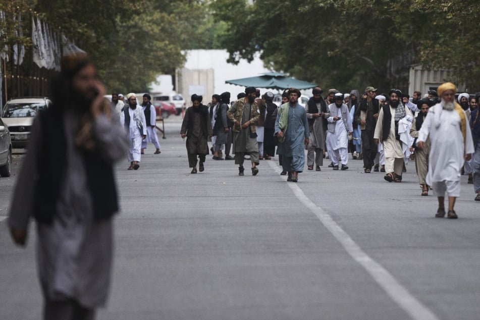 Taliban-Mitglieder laufen auf einer Straße in der Nähe des ehemaligen Präsidentenpalastes in Kabul entlang.