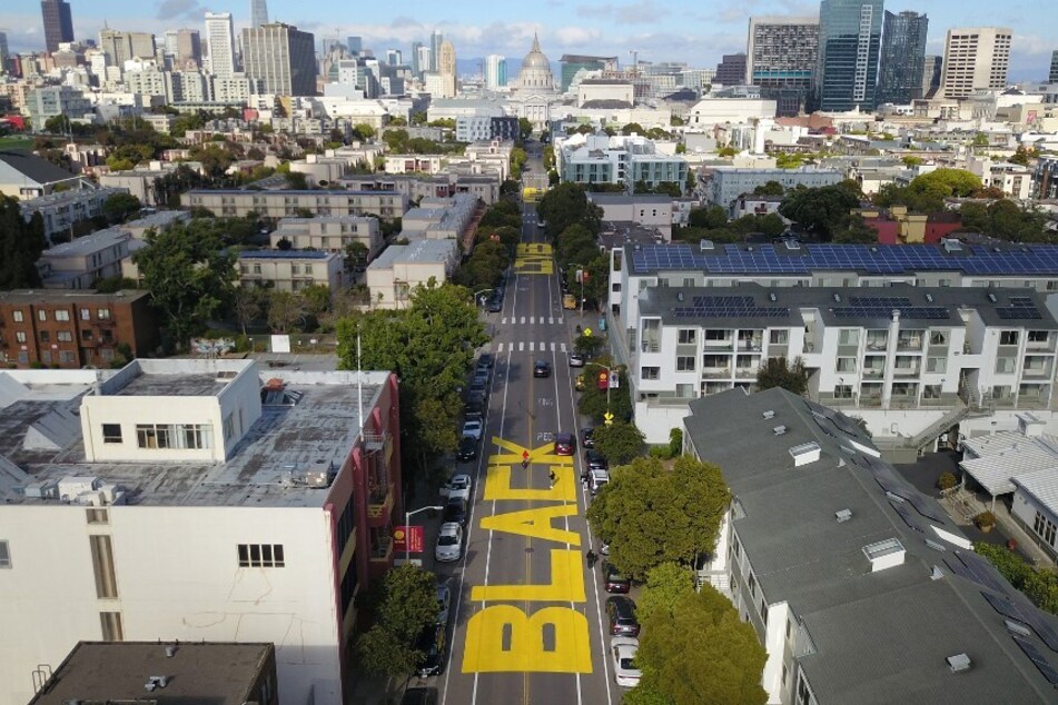 An aerial photo shows a giant street mural reading "Black Lives Matter" spanning three city blocks near City Hall in San Francisco.