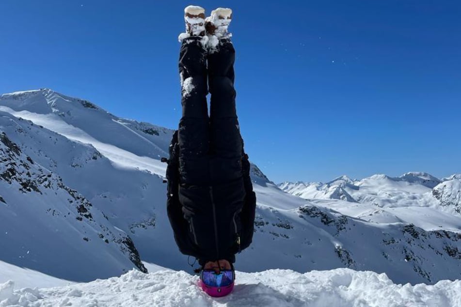 Die sportliche Opernsängerin Barbara Krieger steht in Snowboard-Montur im Gebirgsschnee kopf.