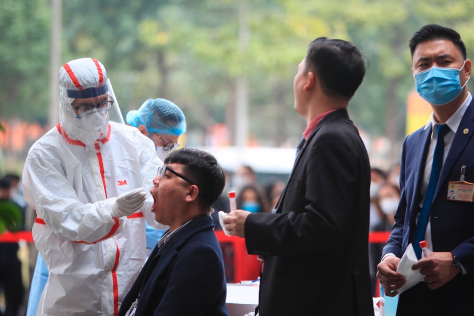 Hanoi: Ein Mitarbeiter des Gesundheitswesens nimmt für einen Corona-Test eine Abstrichprobe von einem Sicherheitsbeamten am Veranstaltungsort des Kongresses der Kommunistischen Partei.