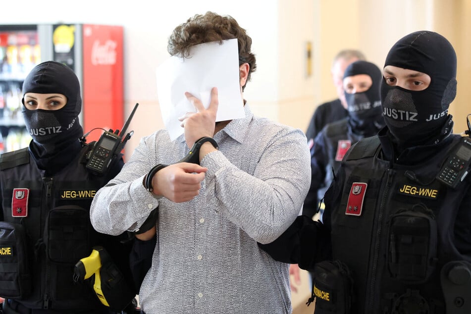 The defendant identified as Beran A. covered his face as he was led into the courtroom by security.