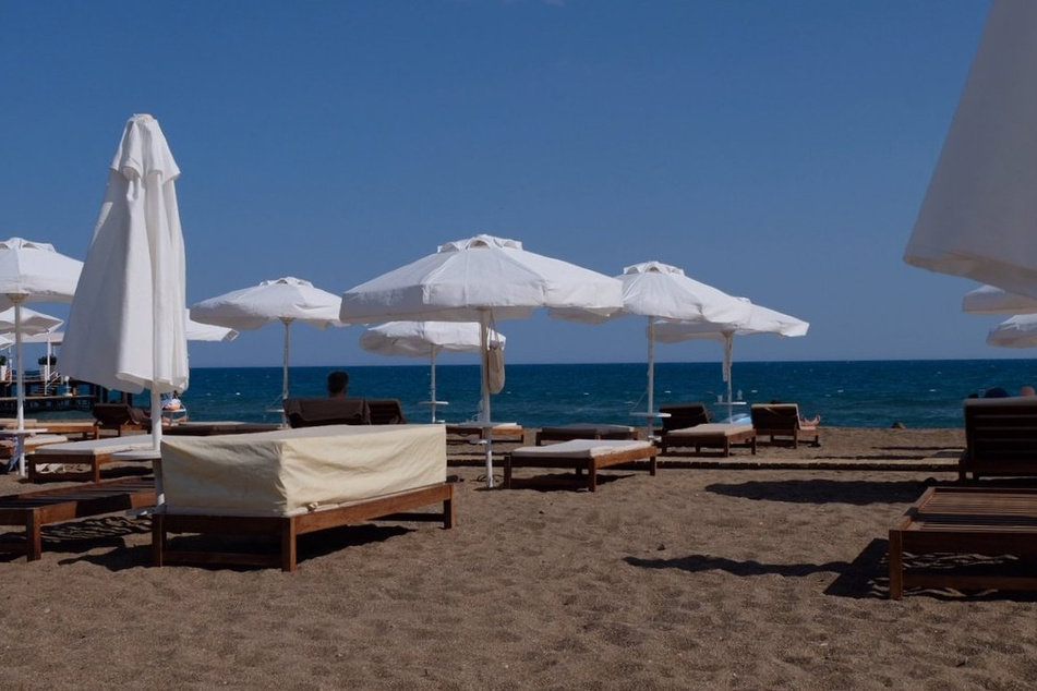 Strandliegen und Sonnenschirme stehen am menschenleeren Strand an einer Hotelanlage. Die Türkei gilt als Corona-Risikogebiet, und auch die Reisewarnung wird wohl nicht zeitnah aufgehoben.