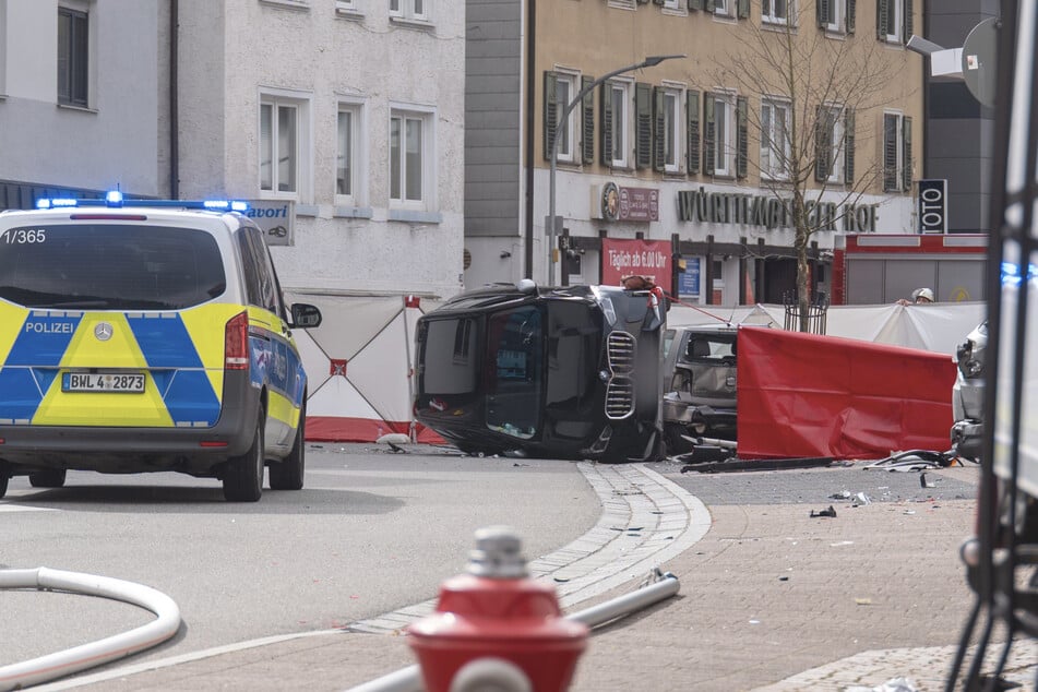 Einsatzkräfte sperrten den Unfallbereich mit Sichtschutz ab. Ein BMW lag davor auf der Seite, ein Kleinwagen stand stark beschädigt dahinter.