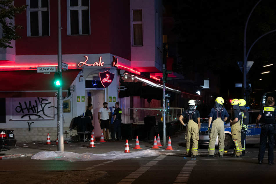 Feuerwehrleute stehen vor der Shisha-Bar in der Müllerstraße in Berlin-Wedding, wo in der Nacht zum 21. Juni knapp 30 Schüsse auf drei Männer abgefeuert wurden.