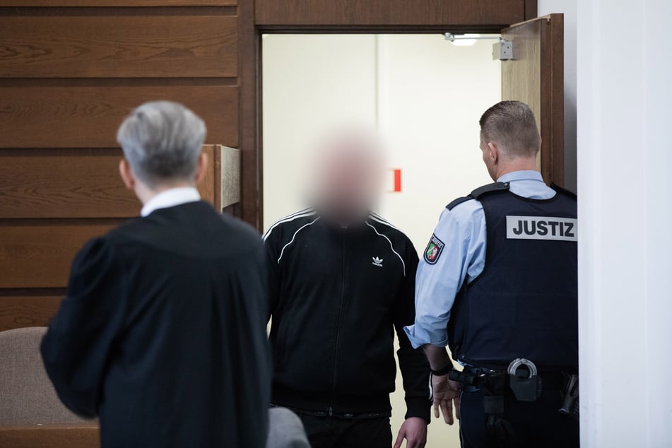 Der Angeklagte wird in einen Gerichtssaal des Landgerichts geführt. Der 22 Jahre alte Mann steht wegen mutmaßlicher Morde mit einem Küchenmesser und einer Grillgabel vor dem Kölner Landgericht.