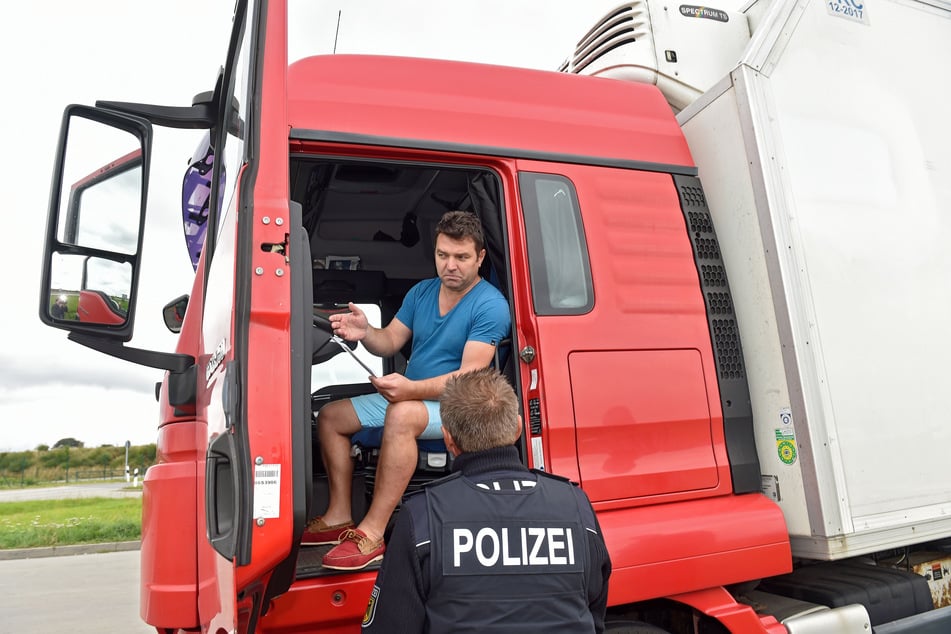 Polizisten kontrollieren einen Lastwagenfahrer. An Sonn- und Feiertagen sollte der Schwerlastverkehr ruhen.