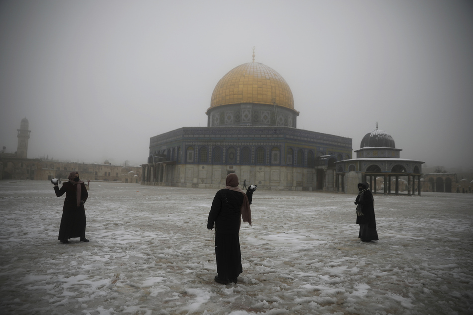 Frauen haben Spaß bei einer Schneeballschlacht am Felsendom in der Altstadt von Jerusalem.