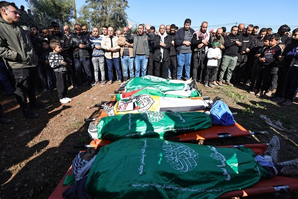 Mourners recite a prayer over the flag-draped bodies of Palestinians killed during an Israeli raid in Jenin in the occupied West Bank, during their funeral on January 7, 2024.