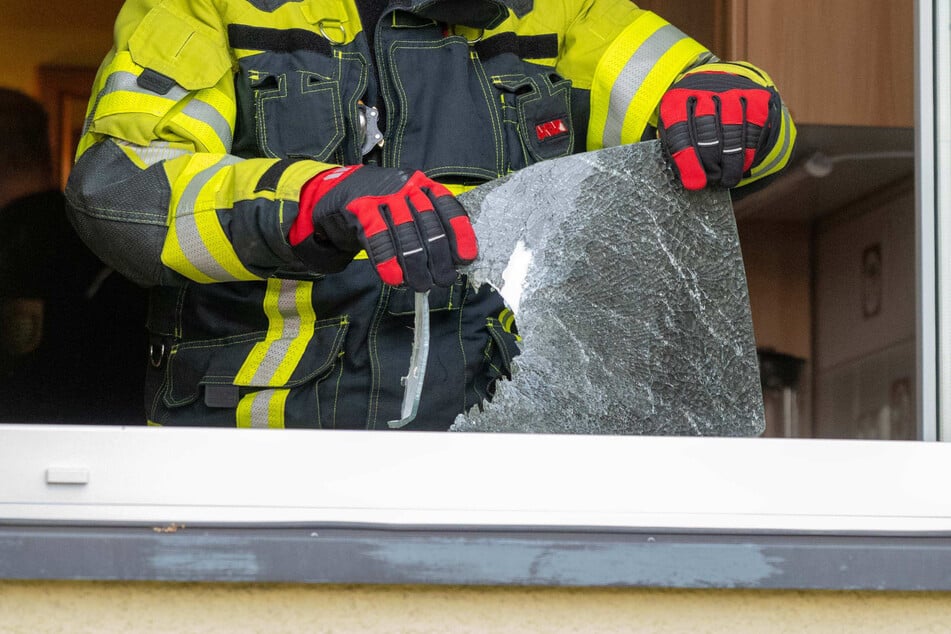 Ein Feuerwehrmann hält in der Brandwohnung die Überreste einer anscheinend eingeschlagenen Glasplatte hoch.