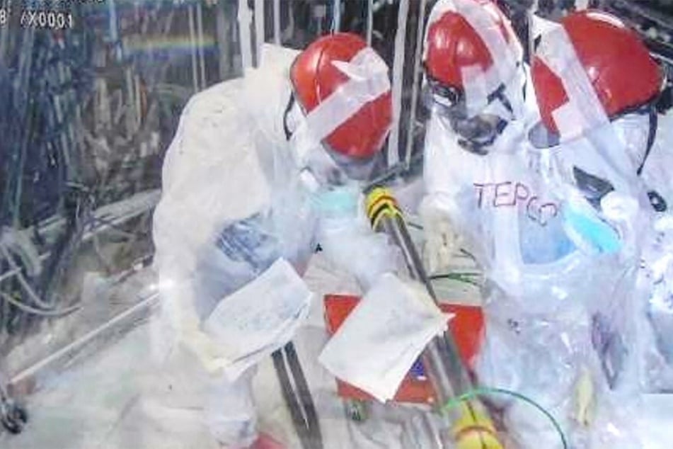 A TEPCO supervisor (c.) and two contractor workers rearrange push pipes in their correct order at the Fukushima Daiichi Nuclear Power Plant.