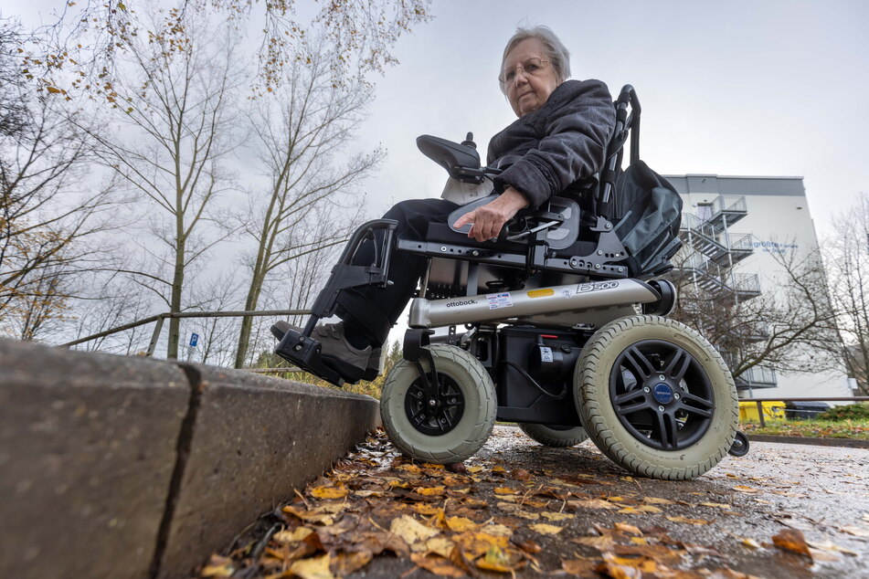 Barrierefreiheit sieht anders aus: Gisela Lindner kann den Bordstein am Fußweg der Johannes-Dick-Straße mit ihrem Rollstuhl nicht überwinden.