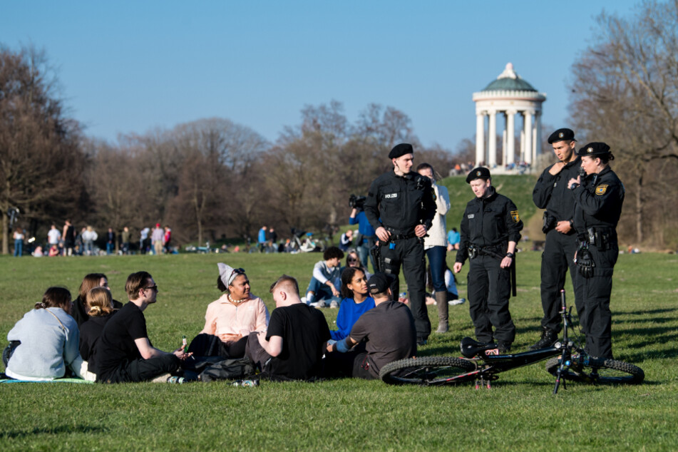 Polizisten reden im Englischen Garten mit einer Gruppe Jugendlicher.