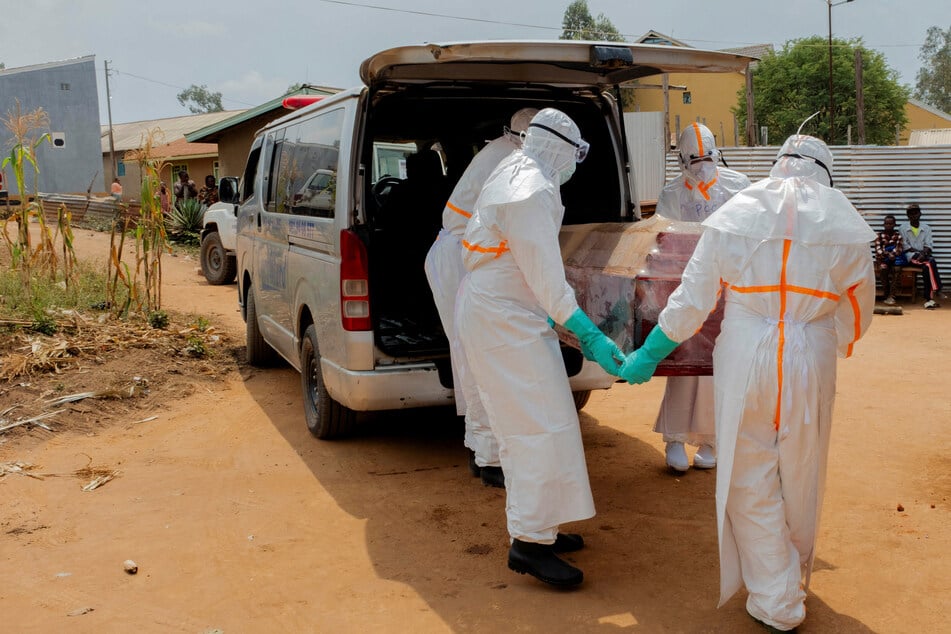 Members of the Civil Protection wearing personal protective equipment carry a wooden coffin with the body of a man, who according to his family died of Ebola, in Bunia, Ituri province, Democratic Republic of Congo, on July 10, 2026.