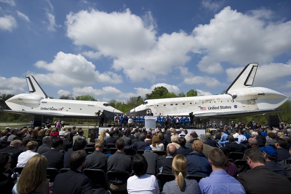 Former US Senator and Astronaut John Glenn speaks as Space Shuttle Discovery and Space Shuttle Enterprise are parked nose to nose during a transfer ceremony at the Smithsonian National Air and Space Museum Steven F. Udvar-Hazy Center in Chantilly, Virginia, April 19, 2012, as the Shuttle Discovery is officially received by the museum and will be placed on permanent display.