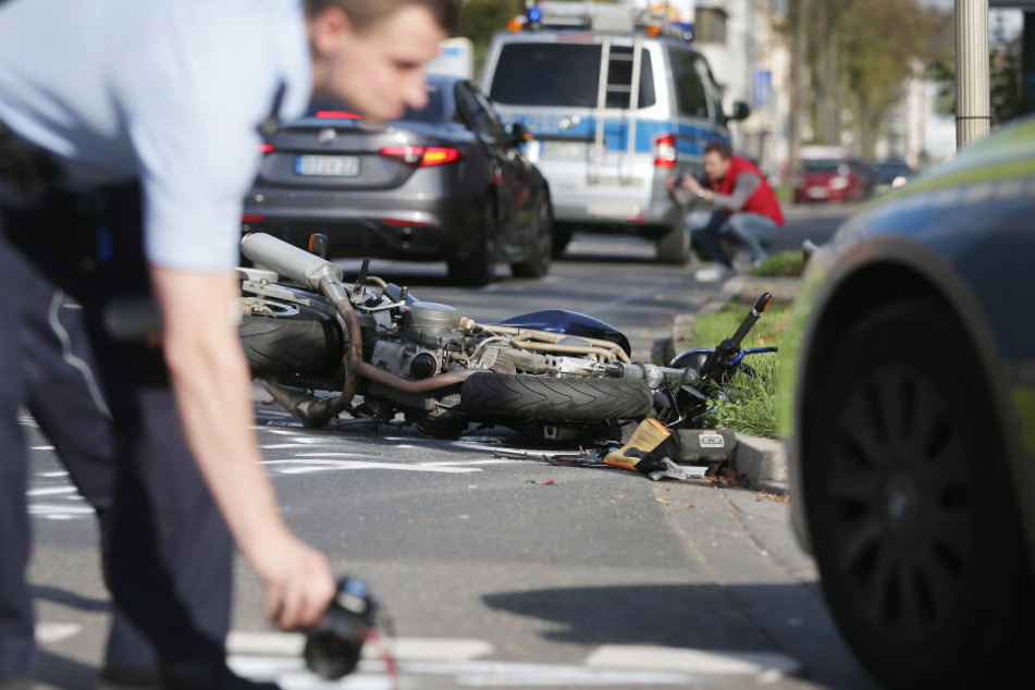 Düsseldorf: Ein Motorrad liegt nach einem Unfall auf der Straße, ein Polizist markiert Spuren.