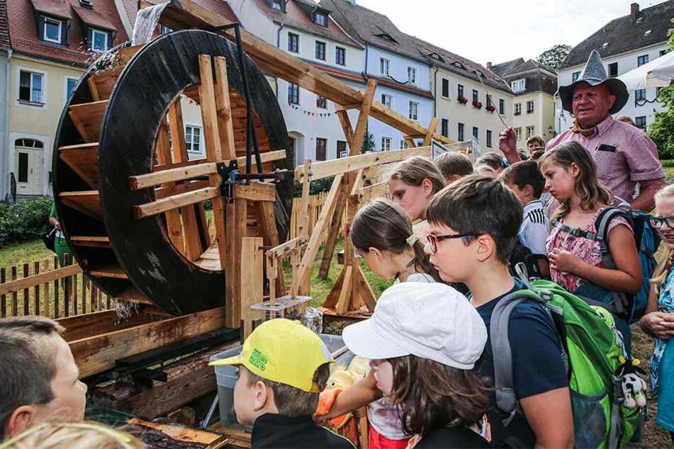 Peter Jungnickel (67, r.) erklärt den Schülern auf dem Marktplatz, wie die Wasserkunst funktioniert.