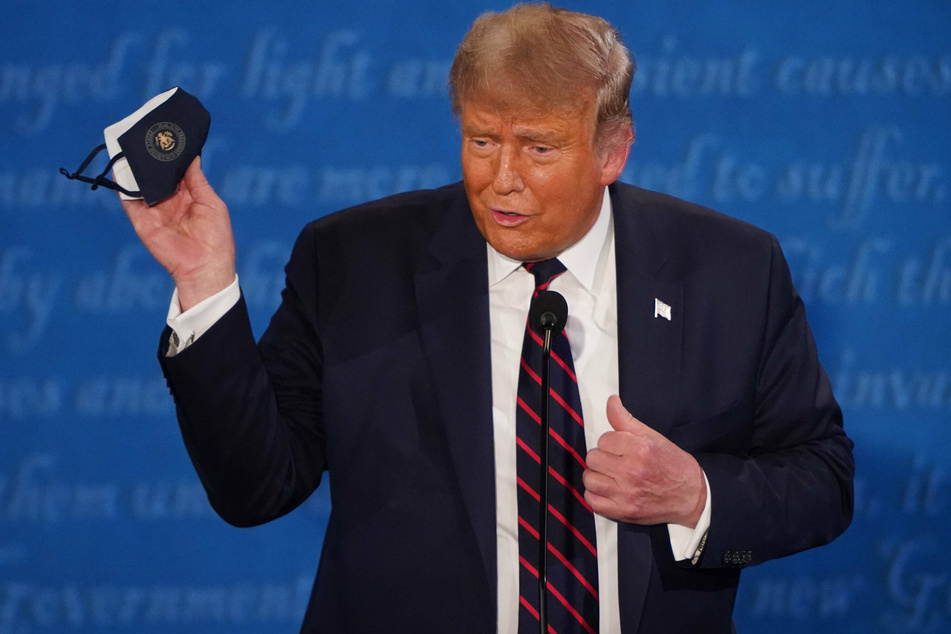 US President Donald Trump holds a mask while speaking at a press conference at the White House in Washington