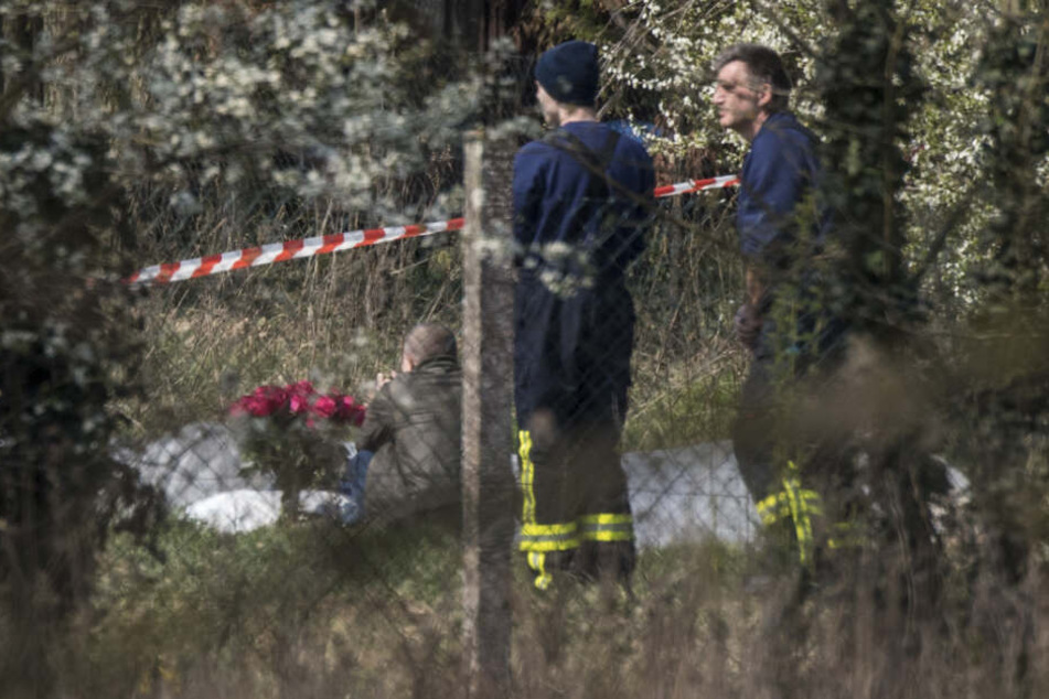Ein Mann betet mit einem Rosenstrauß in der Hand vor dem zerstörten Flugzeug.