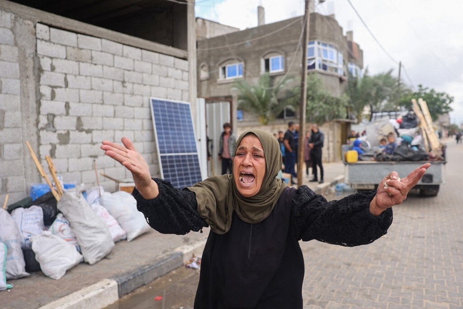 A woman reacts as displaced Palestinians in Rafah in the southern Gaza Strip pack their belongings following an evacuation order by the Israeli army.