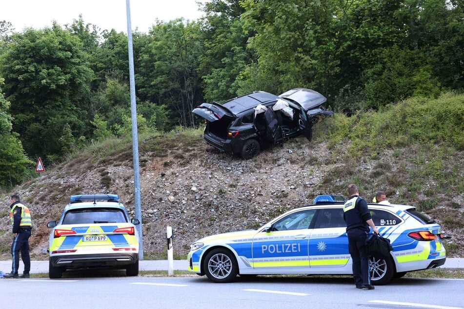 Polizeiautos stehen nahe Marktl an einer Böschung, an der das Fluchtauto verunglückte.
