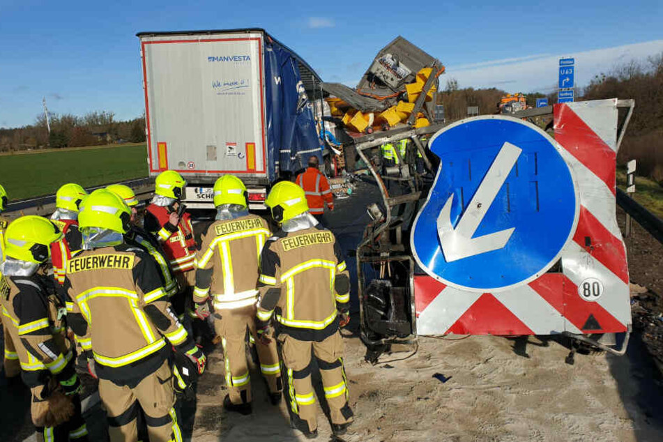 Einsatzkräfte der Feuerwehr stehen vor einem Schilderwagen.