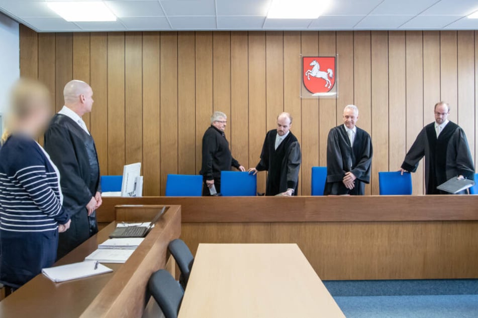 Während die Richter den Raum betreten, steht die Angeklagte (links) mit ihrem Anwalt vor Prozessbeginn im Gerichtssaal.