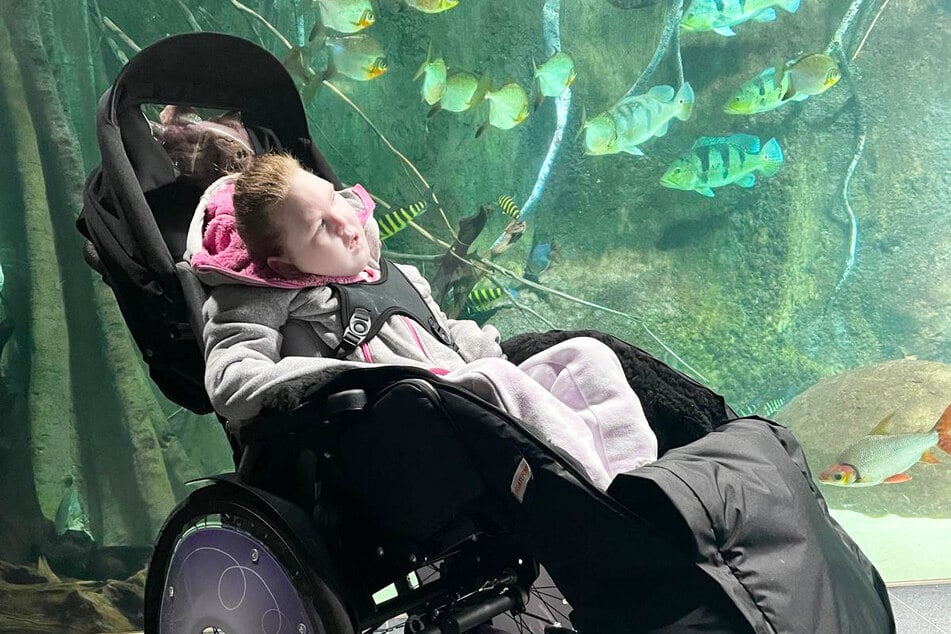 Die Achtjährige kann nicht eigenständig sitzen oder laufen, ist auf einen Rollstuhl angewiesen. Hier steht sie vor einem Aquarium im Leipziger Zoo.