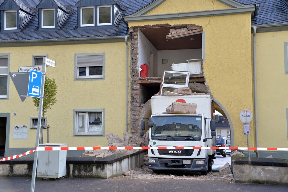 Ein Miet-LKW steckt in einer Hausdurchfahrt fest. Teile eines darüber gelegenen Mehrfamilienhauses sind dabei eingestürzt.