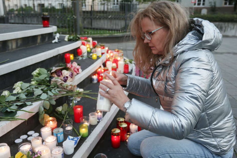 Ute Pfeil aus Düsseldorf legt Blumen auf die Treppe vor der Synagoge und entzündet eine Kerze.