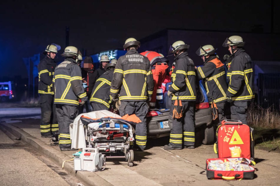 Einsatzkräfte stehen am verunfallten Fahrzeug.