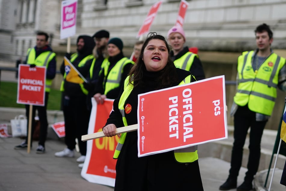 Mitglieder der Gewerkschaft für öffentliche und kommerzielle Dienste (PCS) stehen an einem Streikposten vor dem Büro des britischen Finanzministeriums in London.