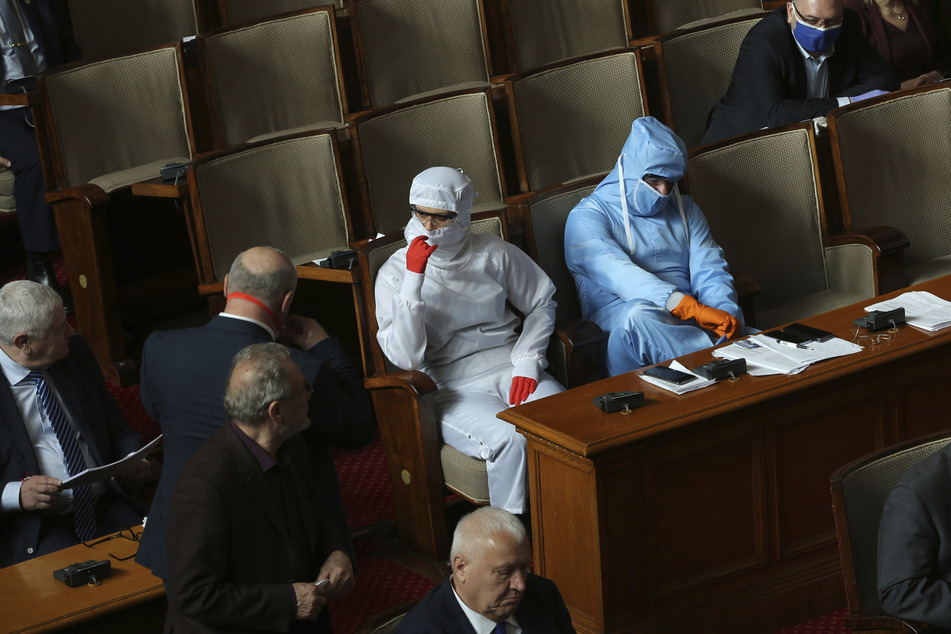 Politiker tragen während der Parlamentssitzung in der bulgarischen Nationalversammlung in Sofia Schutzanzüge.