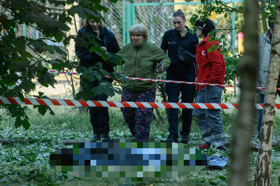 Eine Frau (2.v.l) reagiert auf eine Person, die mutmaßlich bei einem nächtlichen Raketenangriff getötet wurde. Bei einem russischen Raketenangriff auf Kiew sind nach ukrainischen Behörden mindestens drei Menschen ums Leben gekommen, darunter zwei Kinder.