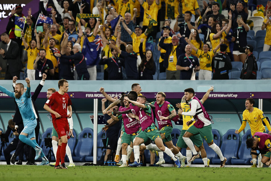 Australian players run onto the field at full time after their win over Denmark.