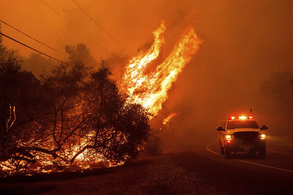 Flammen schlagen aus einem Fahrzeug auf dem Canyon Drive, während das Thompson Fire brennt.