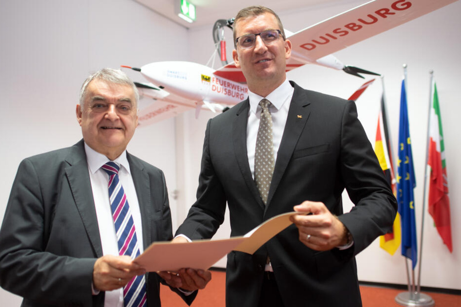 Herbert Reul (CDU,l), Innenminister von Nordrhein-Westfalen und Dennis Göge, Programmkoordinator für Sicherheitsforschung beim Deutschen Zentrum für Luft- und Raumfahrt (DLR), stehen vor einer Drohne der Feuerwehr Duisburg.