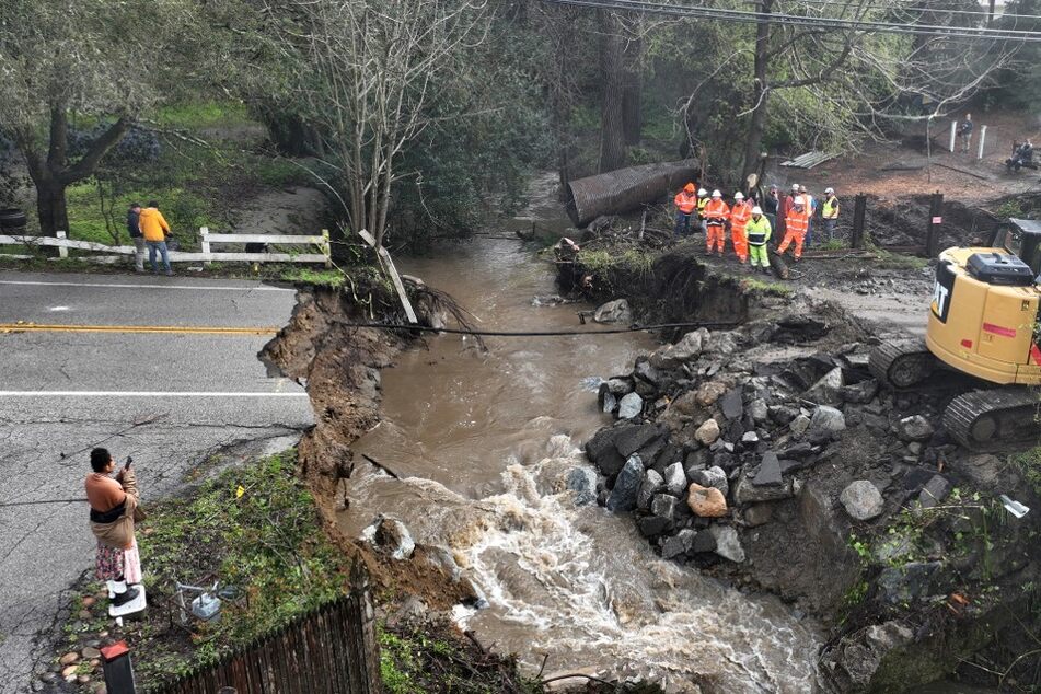 Workers make emergency repairs to a road that was washed out during heavy rains on March 10, 2023, in Soquel, California.