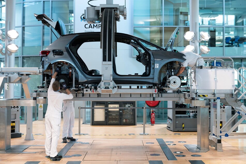 VW-Mitarbeiter bei der Montage eines ID.3 in der Gläsernen Manufaktur in Dresden. Im Rahmen der Debatten um Einsparungen fällt jetzt häufiger der Name dieses Standortes (Archivfoto).