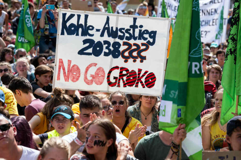 "Kohle Ausstieg 2038??? No Go Kroko" steht auf einem Protestplakat, das Demonstranten in die Höhe halten.