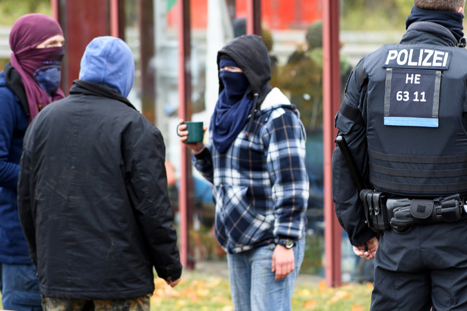 Aktivisten stehen am VW-Werk in Baunatal neben Einsatzkräften der Polizei.