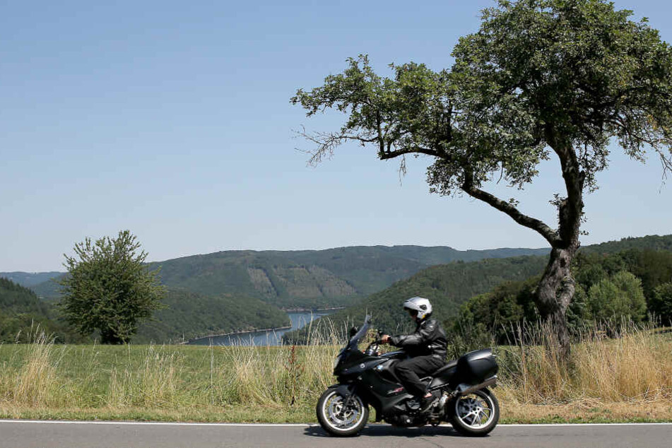 Ein Motorradfahrer fährt in der Nähe von Einruhr, oberhalb der Rurtalsperre durch eine Kurve.