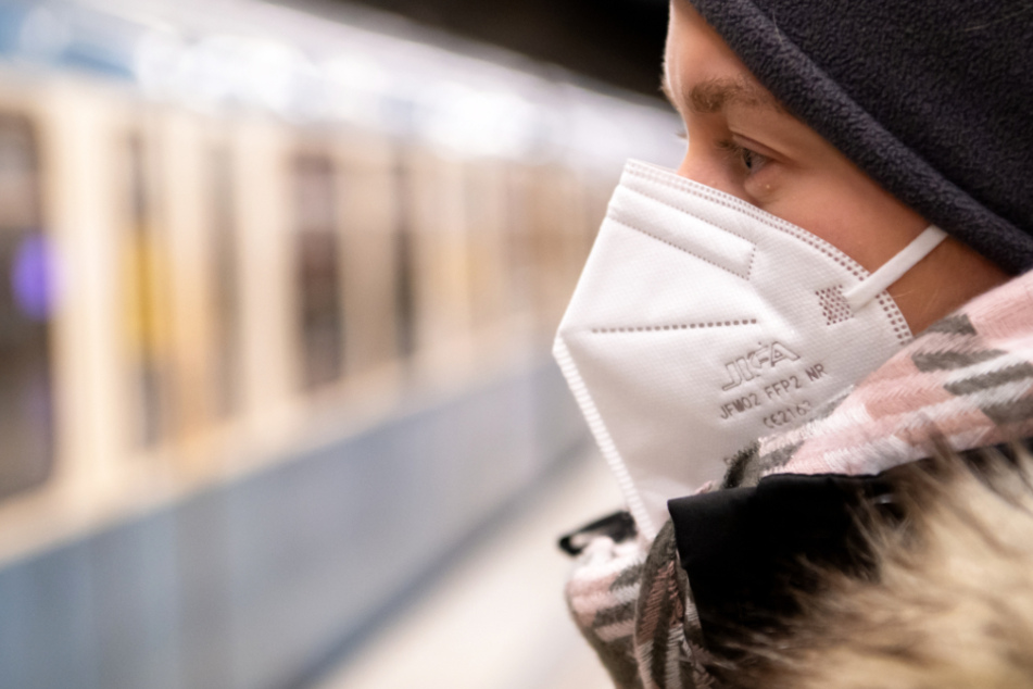 Ein Frau mit FFP2-Maske wartet in einer U-Bahnstation auf die Bahn.