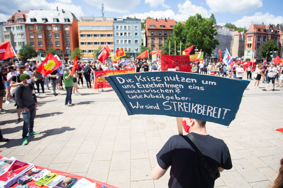 Ein Demonstrant hält ein Plakat mit der Aufschrift „Die Krise nutzen um uns ErzieherInnen eins auszuwischen? Liebe Arbeitgeber: Wir sind Streikbereit“ während der Kundgebung auf dem Stuttgarter Marienplatz.