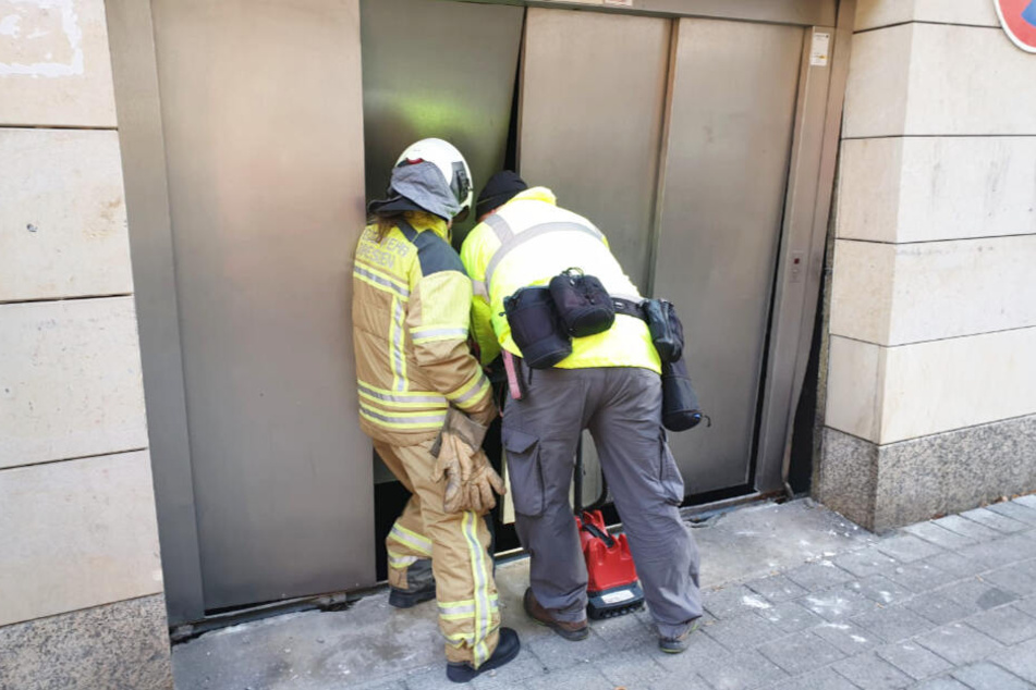 Die Feuerwehrleute schauen zu dem abgestürzten Auto in die Tiefe.