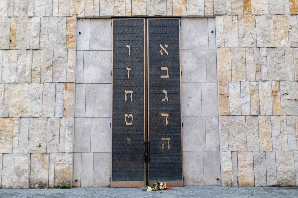 Menschen haben Blumen vor dem Eingangsportal der Münchner Hauptsynagoge Ohel Jakob abgelegt.