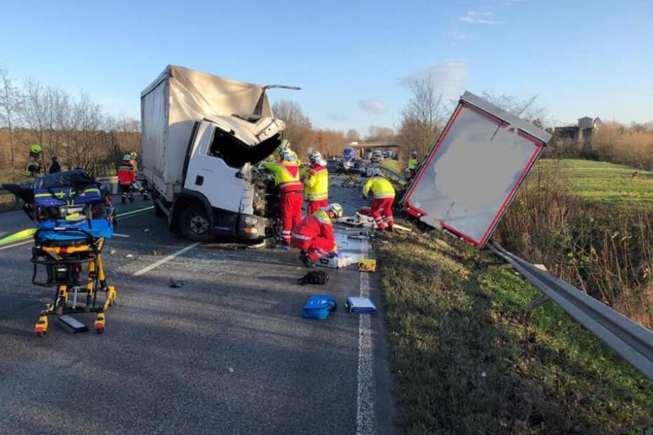 Feuerwehrleute stehen nach einem Lkw-Unfall neben dem zerstörten Fahrerhaus auf der Bundesstraße B1.