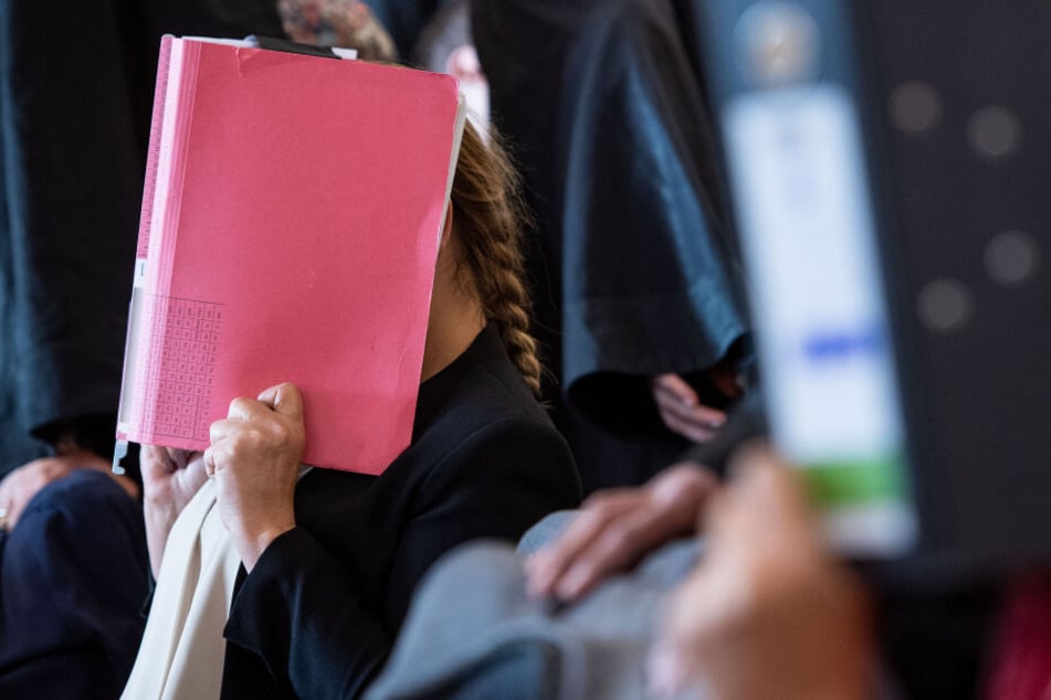 Eine der angeklagten Prostituierten versteckte sich beim Prozessauftakt hinter einer Akte.