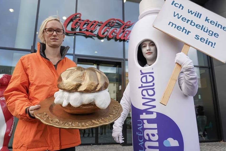 Eine Mitarbeiterin von Food Watch verleiht vor der Deutschland-Zentrale der Coca-Cola GmbH symbolisch "Goldener Windbeutel" an die Firma Coca-Cola für ihr Produkt "Smartwater".