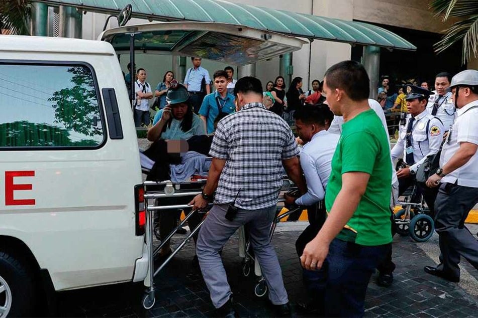 Manila: Rettungskräfte tragen eine Frau zu einem Krankenwagen, nachdem ihr schwindlig wurde.