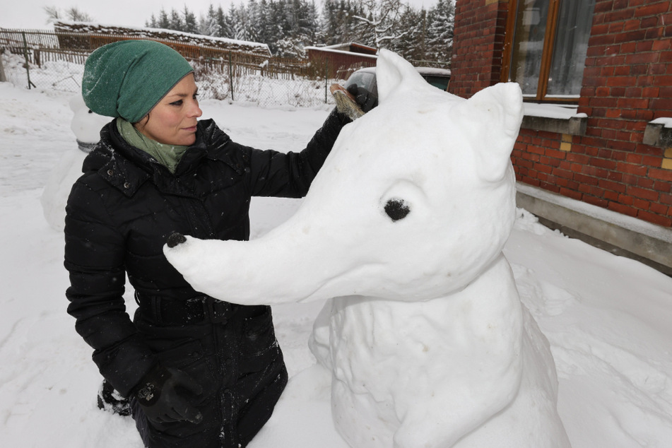 Steinbildhauerin, Jenny Lux steht neben einer ihrer Schneefiguren. Sie hat diese Figuren in der saisonbedingten Winterpause aus einer Laune heraus gebaut.